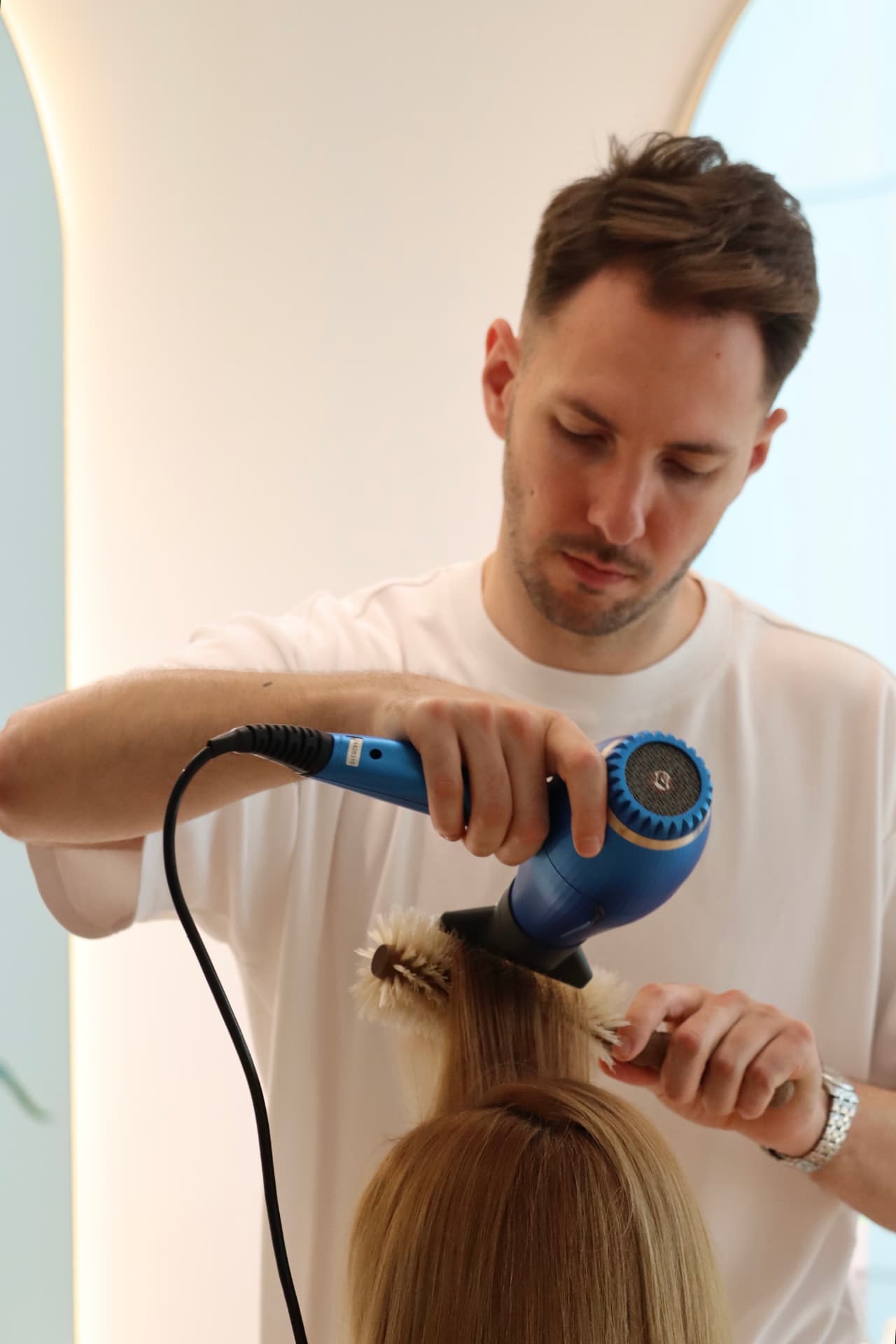 Hairstylist coafând o clientă cu peria rotundă