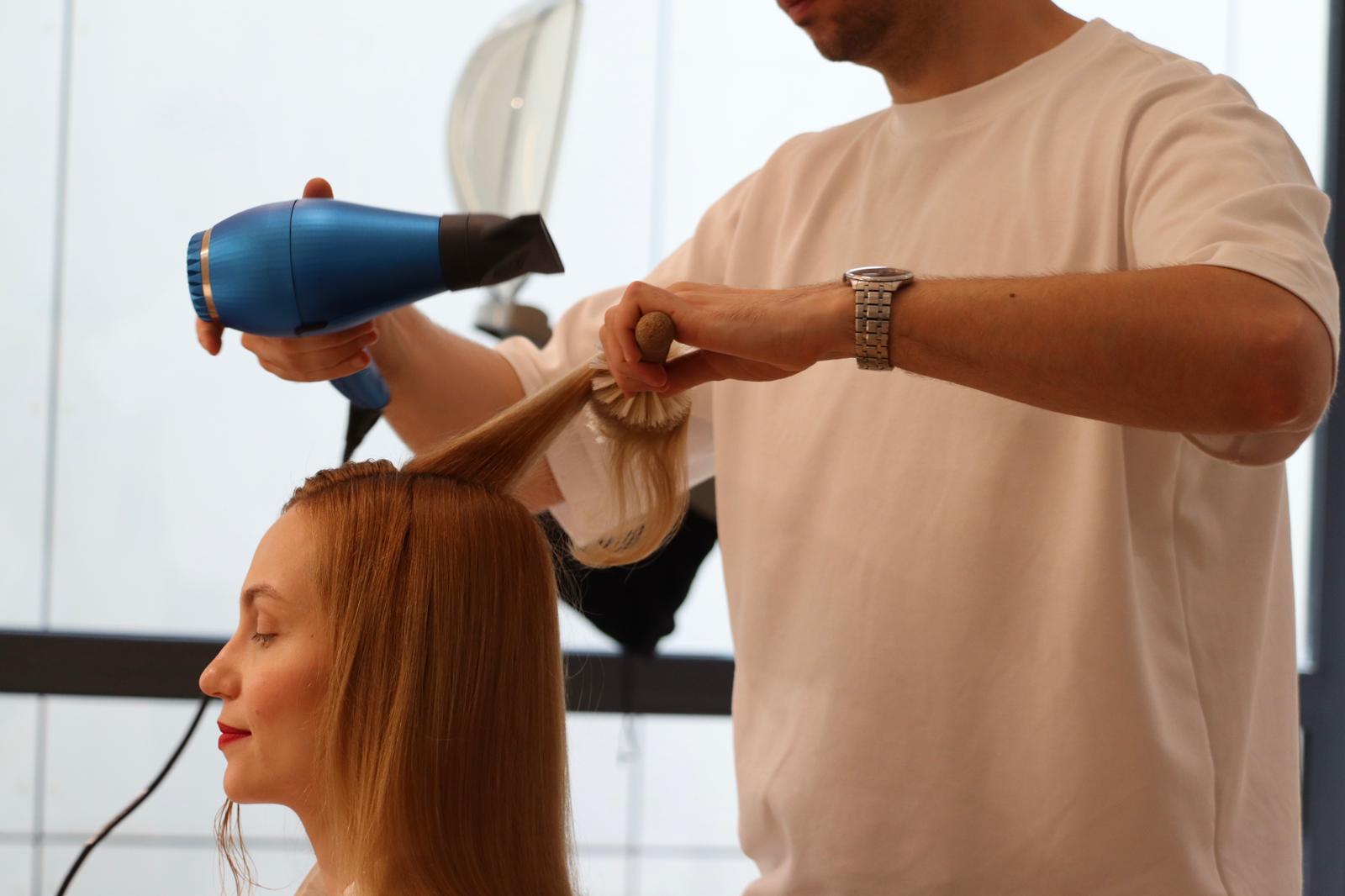 Hairstylist realizând un coafat cu peria rotundă în salon